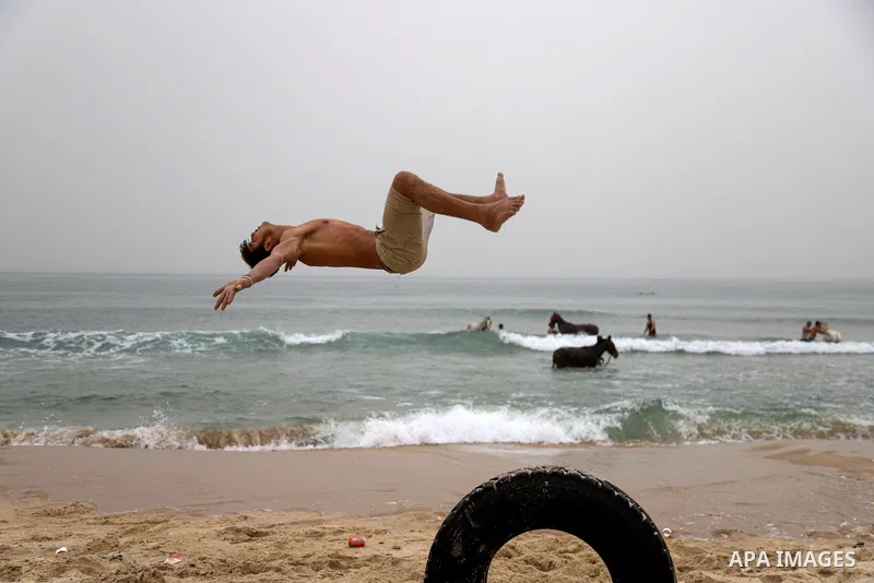 Palestinians enjoy on the Beach during a sand wind (khamsin), of Gaza City on March 23, 2021. Khamsin, chamsin or more commonly known in Egypt as khamaseen is a dry, hot, sandy local wind affecting Egypt and the Levant;...