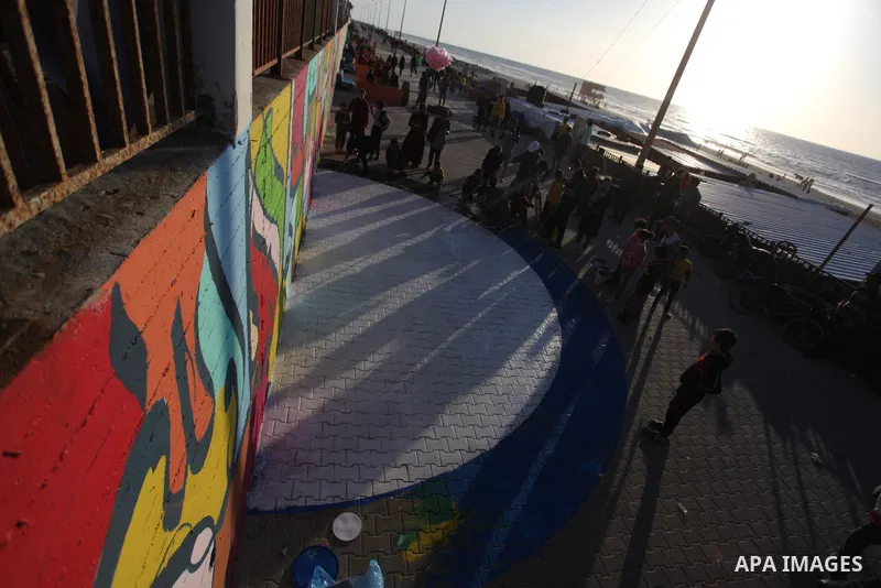 Palestinians from the "Ehsan" campaign team, organize an initiative to color the Gaza pier, entitled "Our Sea is Colored", in Gaza City on March 19, 2021. Photo by Mahmoud Ajjour