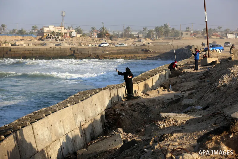 Palestians enjoy during a coldy day at a beach in Khan Younis in the southern Gaza Strip, on March 12, 2021. The country continues to be affected by the trough, and there is a significant decrease in temperatures to beco...