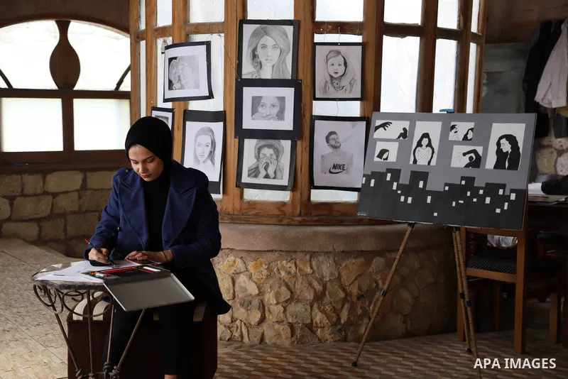 Palestinian artist Zeina Al-Shurafa paints a painting depicting a woman's face, for solidarity with battered woman, in her home in Gaza City on March 10, 2021. Palestinian female victims of domestic violence have little...