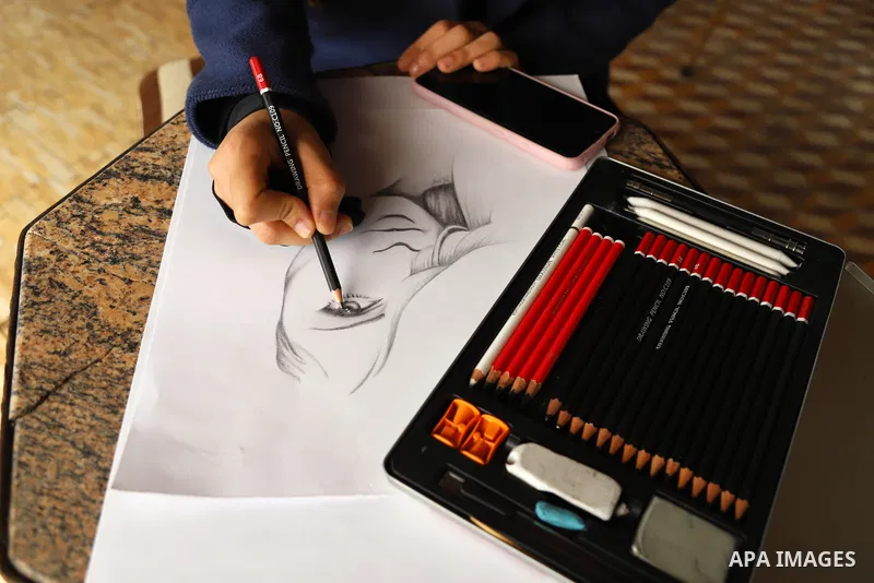 Palestinian artist Zeina Al-Shurafa paints a painting depicting a woman's face, for solidarity with battered woman, in her home in Gaza City on March 10, 2021. Palestinian female victims of domestic violence have little...