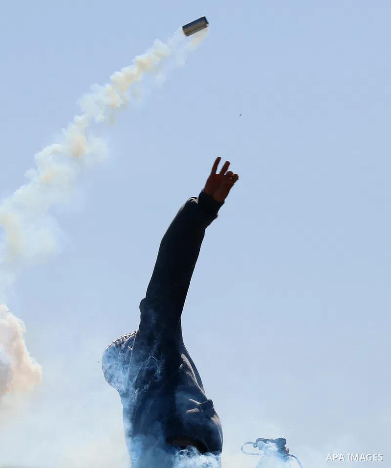 A Palestinian protester returns throwing a tear gas canister at the Israeli forces during a demonstration against the expansion of settlements, in Beit Dajan in the Israeli-occupied West Bank on February 26, 2021. The se...
