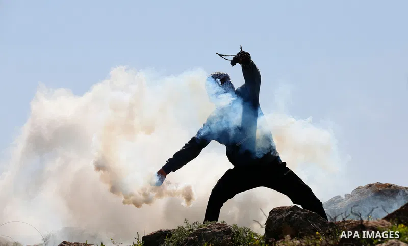 A Palestinian protester returns throwing a tear gas canister at the Israeli forces during a demonstration against the expansion of settlements, in Beit Dajan in the Israeli-occupied West Bank on February 26, 2021. The se...