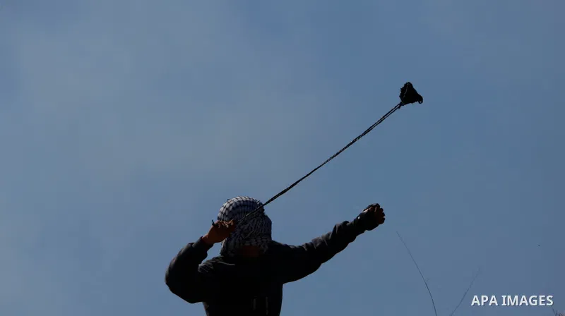 Palestinian protesters hurl a stones towards Israeli security forces during a demonstration against the expansion of settlements, in Beit Dajan in the Israeli-occupied West Bank on February 26, 2021. The settler populati...