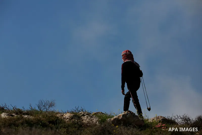 Palestinian protesters hurl a stones towards Israeli security forces during a demonstration against the expansion of settlements, in Beit Dajan in the Israeli-occupied West Bank on February 26, 2021. The settler populati...