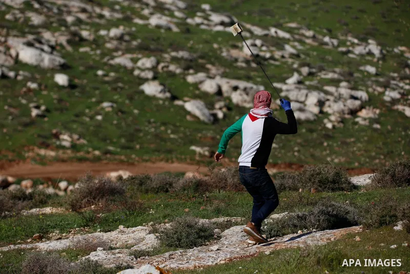 Palestinian protesters hurl a stones towards Israeli security forces during a demonstration against the expansion of settlements, in Beit Dajan in the Israeli-occupied West Bank on February 26, 2021. The settler populati...
