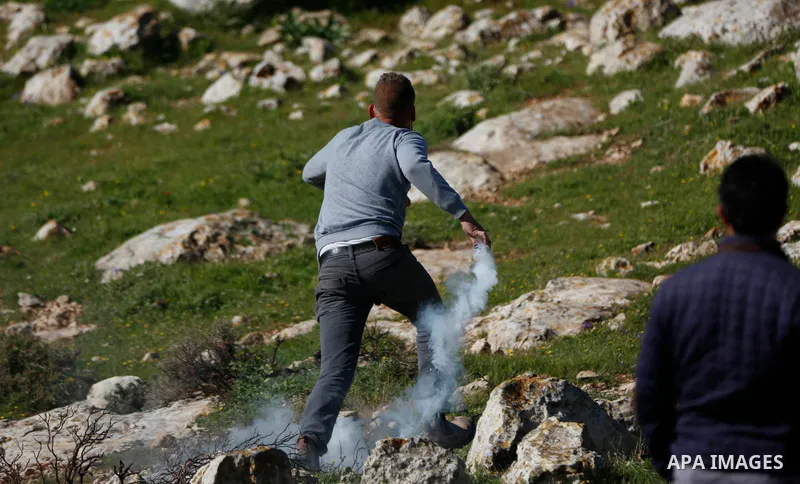 Palestinian protesters hurl a stones towards Israeli security forces during a demonstration against the expansion of settlements, in Beit Dajan in the Israeli-occupied West Bank on February 26, 2021. The settler populati...