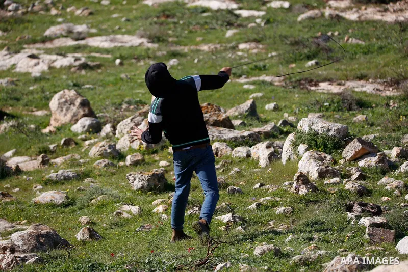 Palestinian protesters hurl a stones towards Israeli security forces during a demonstration against the expansion of settlements, in Beit Dajan in the Israeli-occupied West Bank on February 26, 2021. The settler populati...