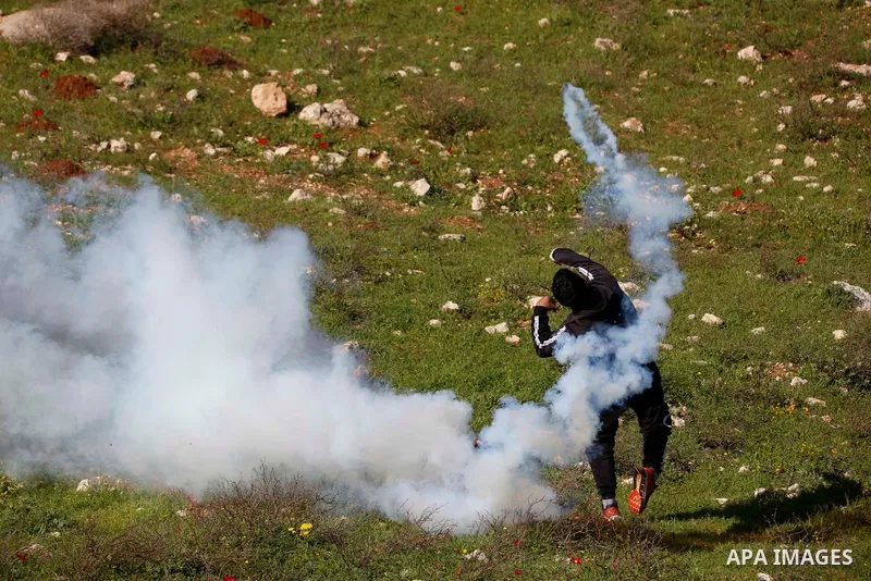 A Palestinian protester returns throwing a tear gas canister at the Israeli forces during a demonstration against the expansion of settlements, in Beit Dajan in the Israeli-occupied West Bank on February 26, 2021. The se...