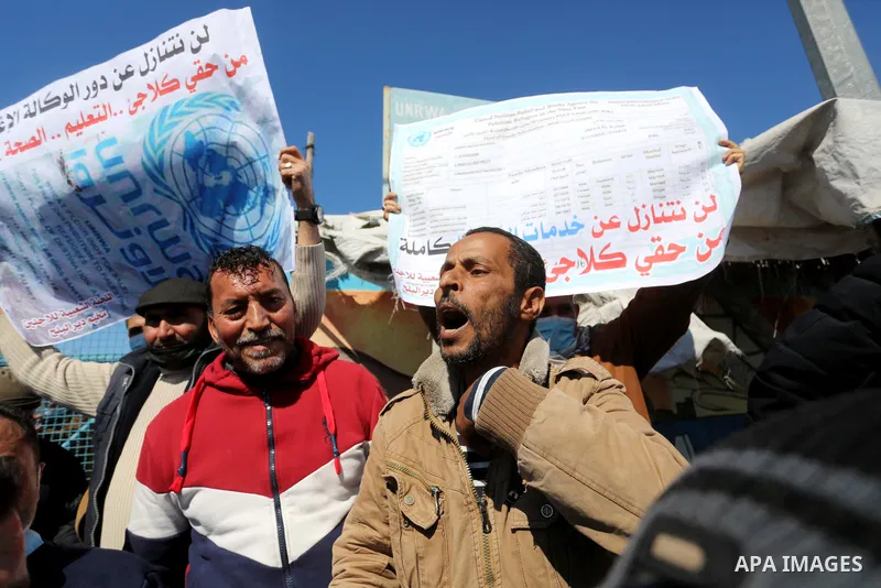 Palestinians take part in a protest against the reduction of the food basket provided by UNRWA, in front of the its aid distribution center, in Deir Al-Balah camp in the central Gaza Strip, on February 21, 2021. Palestin...