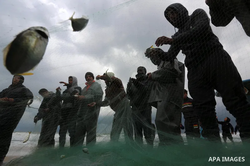 Palestinian fishermen collect caught fish from their nets on the beach in Deir al-Balah, in the central of Gaza Strip, on February 19, 2021. The bad weather and snow that hit Palestine yesterday led to the disruption of...