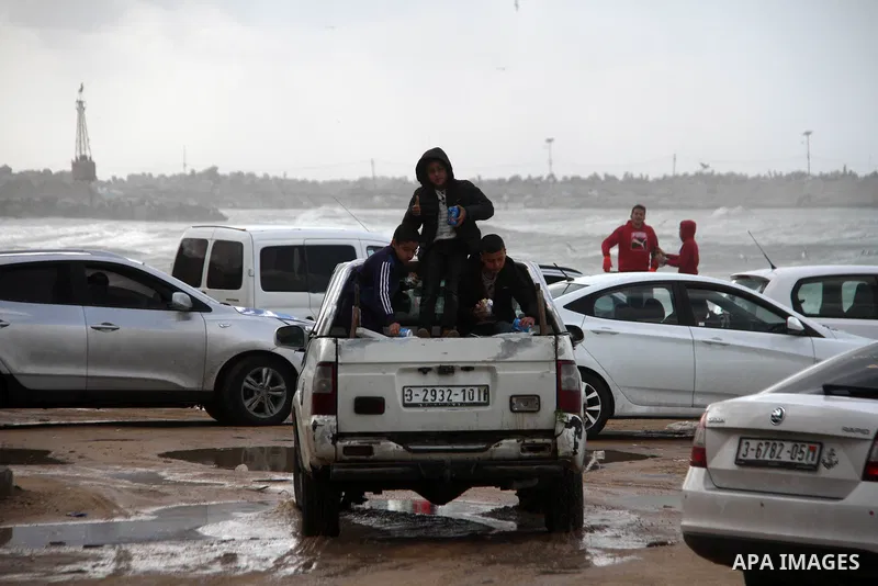 Palestians enjoy during a rainy day, at a beach in Gaza City, on February 18, 2021. The bad weather and snow that hit Palestine yesterday and is expected to continue today caused damage to homes, mainly in the Gaza Strip...