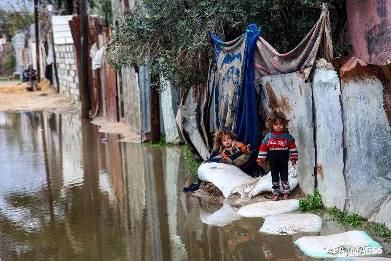 Palestinians walk in a street flooded by rain water during a stormy day, in Beit Lahia in the northern Gaza Strip on February 18, 2021. In the Gaza Strip, several people were hurt and damage caused to homes in various ar...