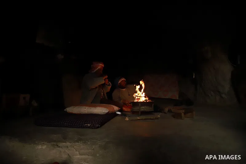 Members of the Palestinian Hammada family sit inside a cave warm themselves by a fire during a rainy day, in Yatta, south of the West Bank of Hebron on February 17, 2021. After Israeli forces demolished their home. Over...