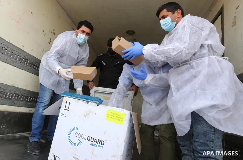 Palestinian health workers unload the first arriving shipment of doses of Russia's Sputnik V vaccine for COVID-19 coronavirus disease, on the Palestinian side of the Kerem Shalom border crossing south of Rafah in the sou...
