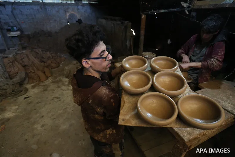 Palestinian Sayed Atallah, 40, works at a pottery workshop with thier sons in Deir al-Balah in the central Gaza Strip, on February 14, 2021. Pottery is the process and the products of forming vessels and other objects wi...