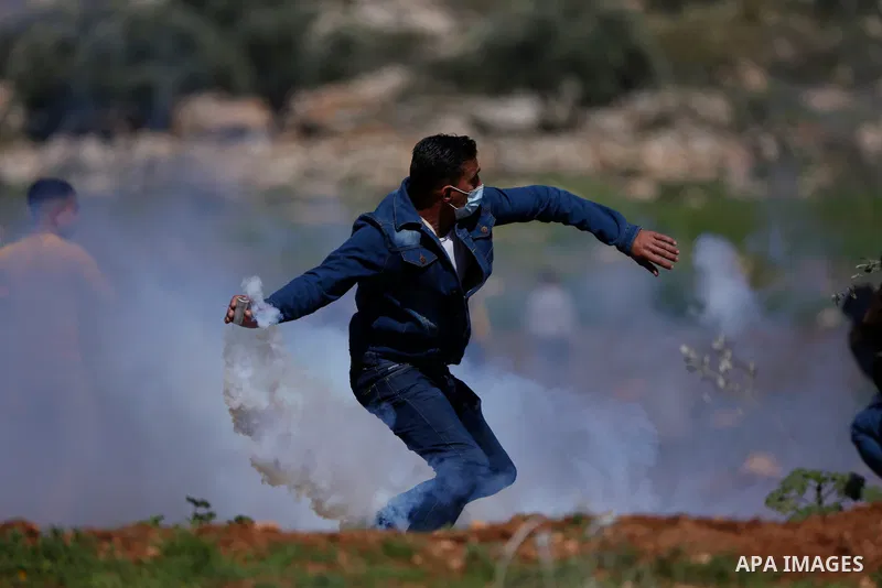 A Palestinian protester returns throwing a tear gas canister at the Israeli forces during a demonstration against the expansion of settlements, in Beit Dajan in the Israeli-occupied West Bank on February 12, 2021. The se...