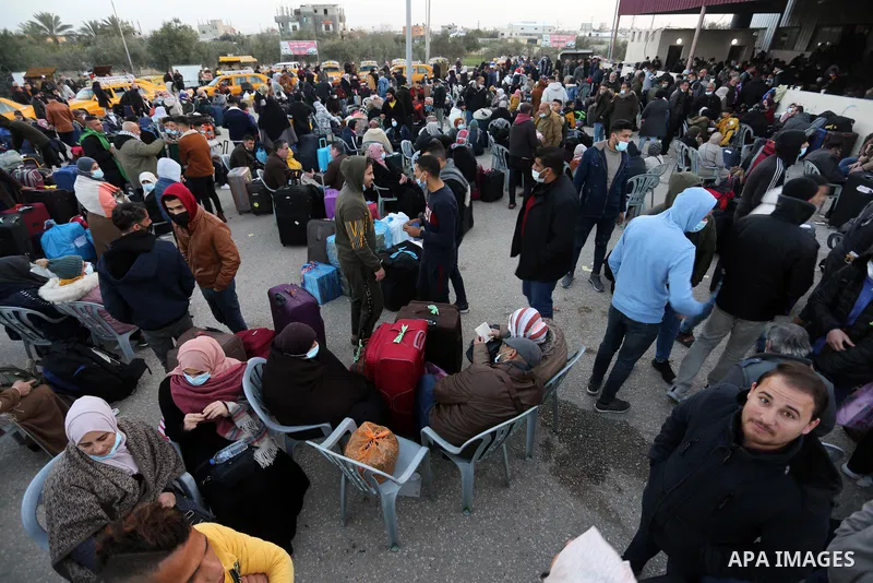 Palestinians wearing protective masks amid the COVID-19 pandemic, as they wait for travel permits to cross into Egypt through the Rafah border crossing, in Rafah in the southern of Gaza Strip, on February 2, 2021, after...