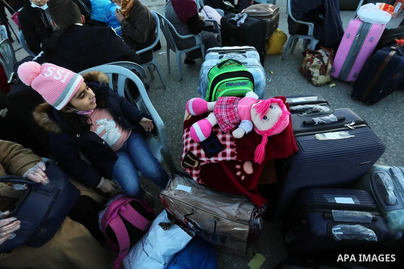Palestinians wearing protective masks amid the COVID-19 pandemic, as they wait for travel permits to cross into Egypt through the Rafah border crossing, in Rafah in the southern of Gaza Strip, on February 1, 2021, after...