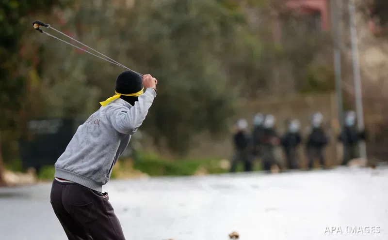 Palestinian protesters hurl a stone towards Israeli security forces during clashes following a weekly demonstration against the expropriation of Palestinian land by Israel in the village of Kfar Qaddum, near the West Ban...