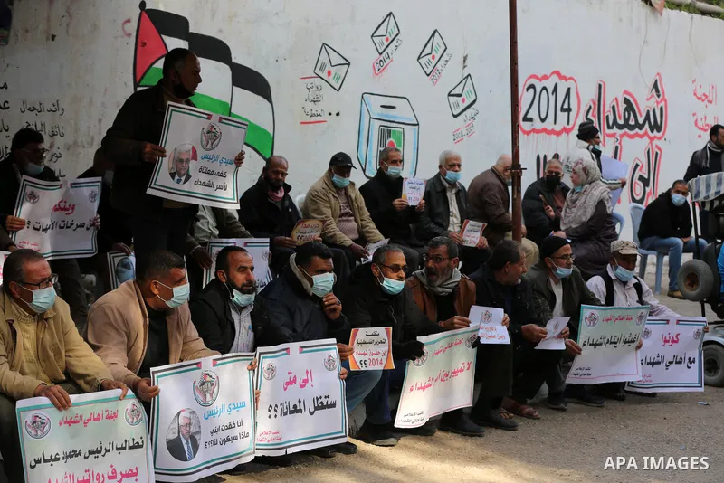 Palestinian families of martyrs and woundeds wearing protective face masks, as they take part in a protest to demand their rights and salaries, in Gaza city, on January 26, 2021. Elections would pose a major risk for Abb...