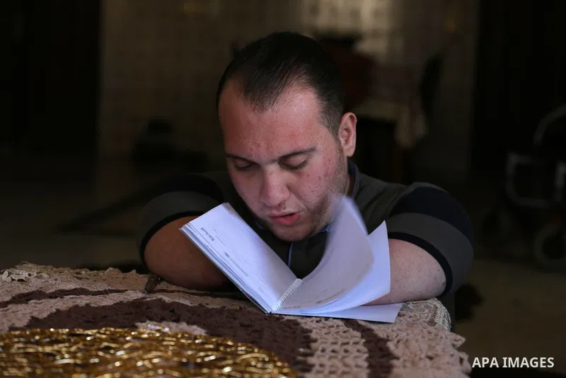 Disabled Palestinian man Youssef Abu Amira turns the pages of his notebook at his home in Gaza City January 25, 2021. Para-karate is the newest evolution of the martial art discipline that evolved in Japan. The new class...