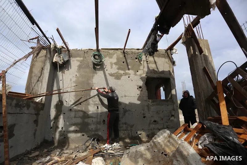 Palestinian men inspect a damaged house near the border fence with Israel, in Maghazi refugee camp in the central Gaza Strip, on January 20, 2021. Israeli tank fire struck a number of sites in the Gaza Strip, including a...
