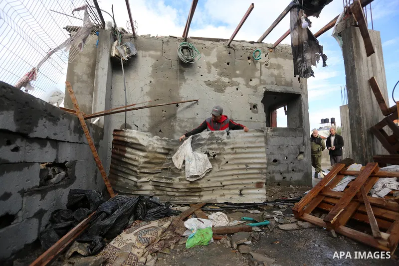 Palestinian men inspect a damaged house near the border fence with Israel, in Maghazi refugee camp in the central Gaza Strip, on January 20, 2021. Israeli tank fire struck a number of sites in the Gaza Strip, including a...