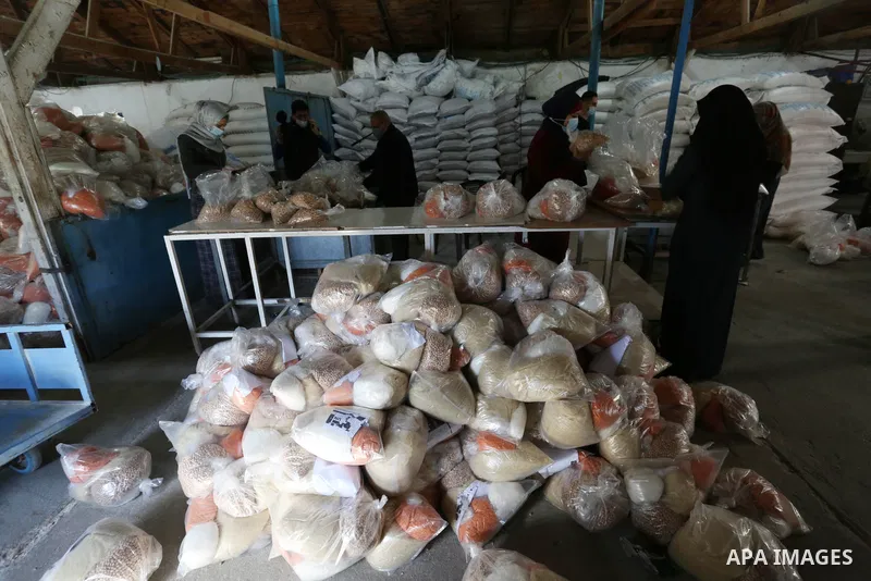 Palestinian women employees at the United Nations Relief and Works Agency for Palestinian Refugees (UNRWA) wearing protective masks, prepare food aid rations at an aid distribution center, amid the outbreak of the corona...