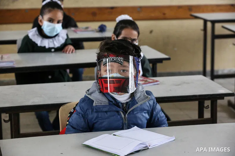 Palestinian students wear protective face masks, listen to their teacher as schools gradually reopen amid the coronavirus disease (COVID-19) outbreak, at their school in Khan Younis in the southern of Gaza strip, on Janu...