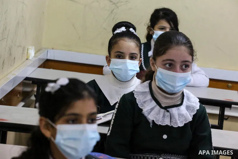 Palestinian students wear protective face masks, listen to their teacher as schools gradually reopen amid the coronavirus disease (COVID-19) outbreak, at their school in Khan Younis in the southern of Gaza strip, on Janu...