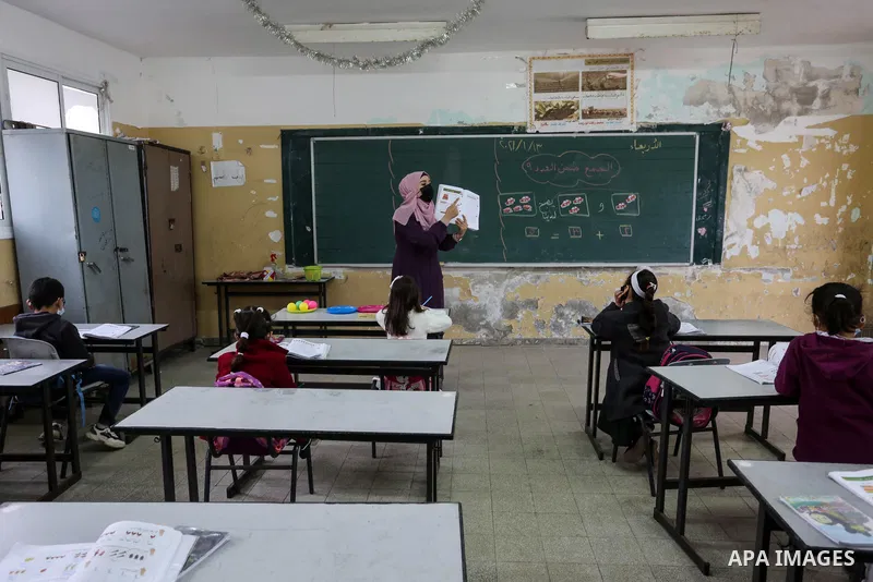 Palestinian students wear protective face masks, listen to their teacher as schools gradually reopen amid the coronavirus disease (COVID-19) outbreak, at their school in Khan Younis in the southern of Gaza strip, on Janu...