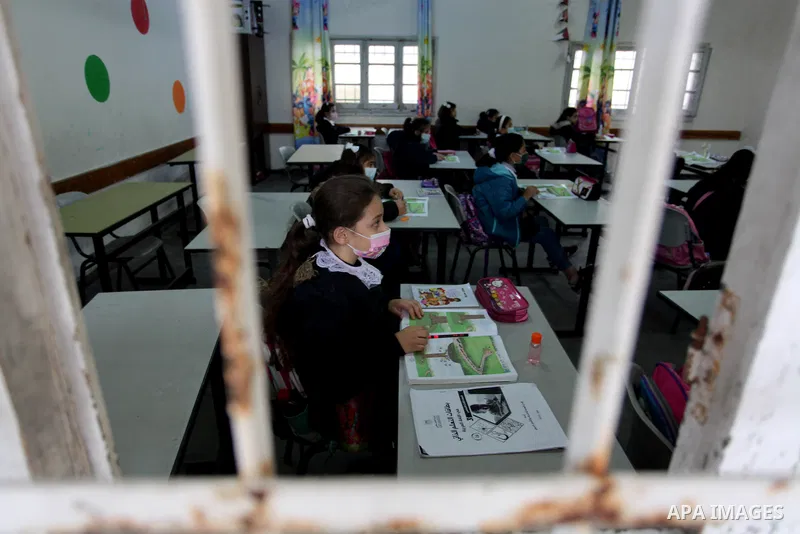 Palestinian students wear protective face masks, listen to their teacher as schools gradually reopen amid the coronavirus disease (COVID-19) outbreak, at their school in Gaza city, on January 13, 2021. In a written state...