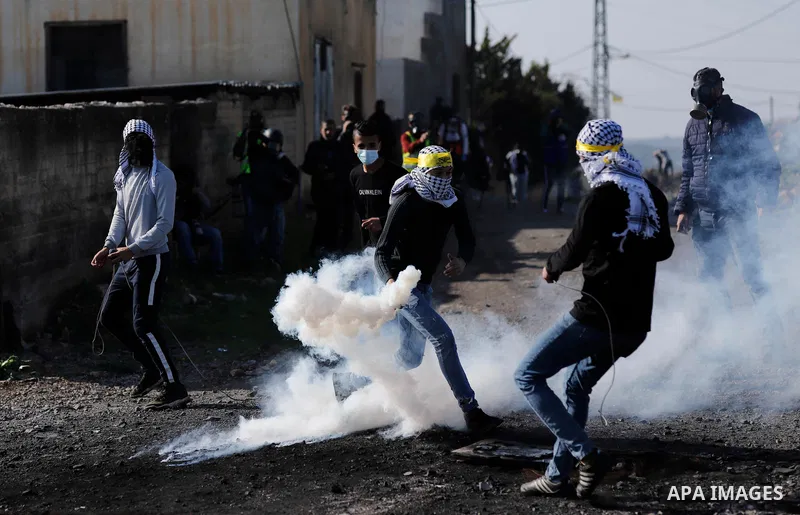 A Palestinian protester returns throwing a tear gas canister at the Israeli forces during clashes following a weekly demonstration against the expropriation of Palestinian land by Israel in the village of Kfar Qaddum, ne...