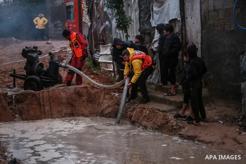 Palestinian firefighters pull water from streets following torrential rains that hit the northern Gaza city on January 16, 2022. Photo by Mohammed Dahman