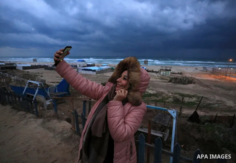 A Palestinian woman takes a selfie on the beach of Gaza sea during a heavy storm "Elpis" on January 26, 2022. Very cold conditions are expected today in Palestine as a low-pressure polar front is expected to hit the coun...