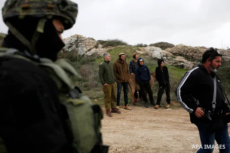 Israeli settlers stand as Palestinians, Israeli activists and members of Knesset plant olive trees near outpost of Givat Ronen in Burin village, near the West Bank city of Nablus on February 4, 2022. Photo by Shadi Jarar...