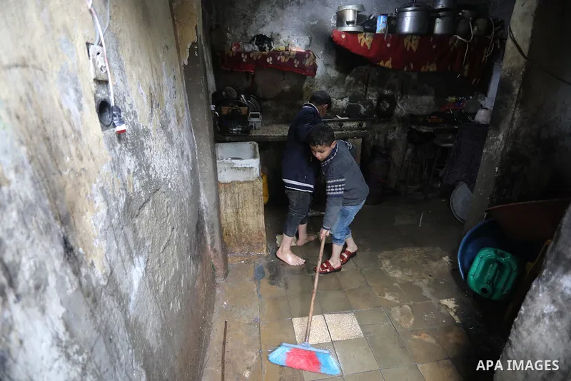 Palestinian woman sits with her children at their home on a rainy day in Deir Al-Balah camp in the central Gaza Strip on February 19, 2022. Poor family consist of 12 members who face difficult life and the high cost of l...