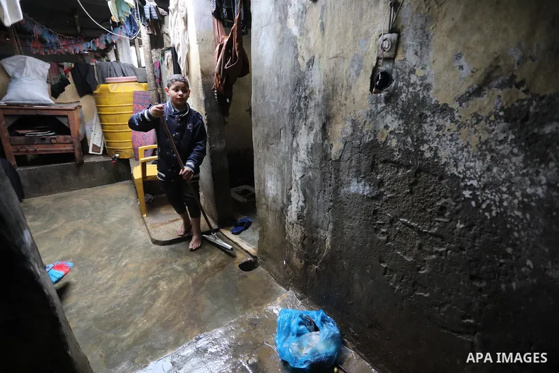Palestinian woman sits with her children at their home on a rainy day in Deir Al-Balah camp in the central Gaza Strip on February 19, 2022. Poor family consist of 12 members who face difficult life and the high cost of l...