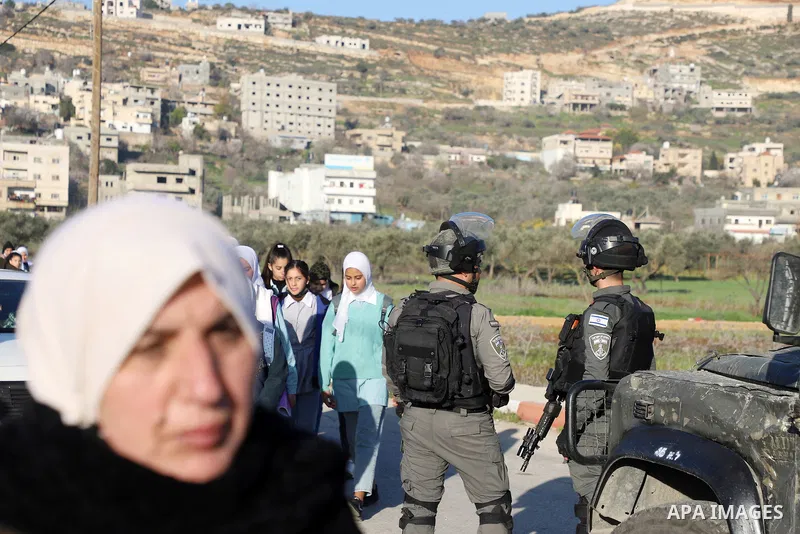 Palestinian students walk to their schools from the main road in al-Lubban al-Sharqiya village, south of Nablus city, in the West Bank on February 23, 2022. Dozens of rampaging Israeli settler fanatics today attacked the...