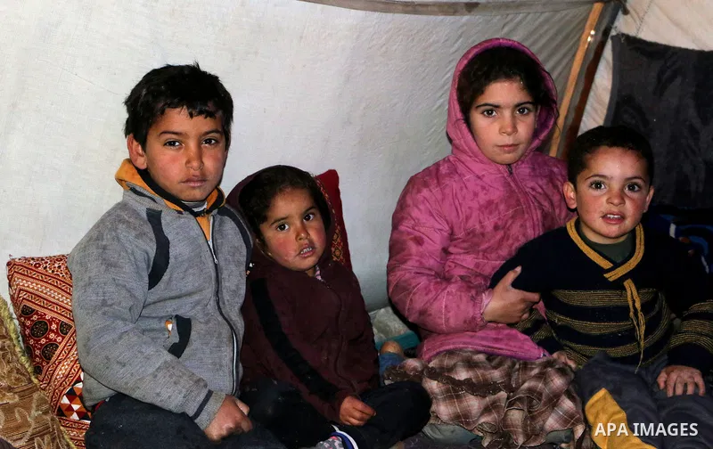 Syrian refugees play near their tents during a winter season, outside the Syrian city of Azaz on Syria's northern border with Turkey, on March 18, 2022. Photo by Samir Abed.