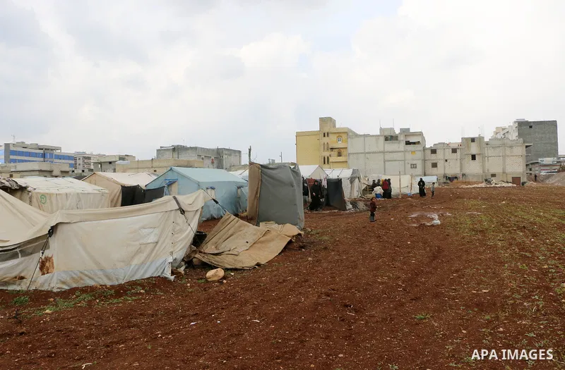 Syrian refugees play near their tents during a winter season, outside the Syrian city of Azaz on Syria's northern border with Turkey, on March 18, 2022. Photo by Samir Abed.