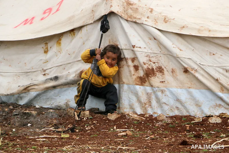 Syrian refugees play near their tents during a winter season, outside the Syrian city of Azaz on Syria's northern border with Turkey, on March 18, 2022. Photo by Samir Abed.