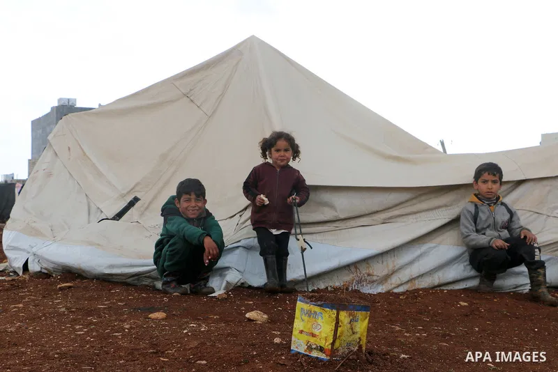 Syrian refugees play near their tents during a winter season, outside the Syrian city of Azaz on Syria's northern border with Turkey, on March 18, 2022. Photo by Samir Abed.