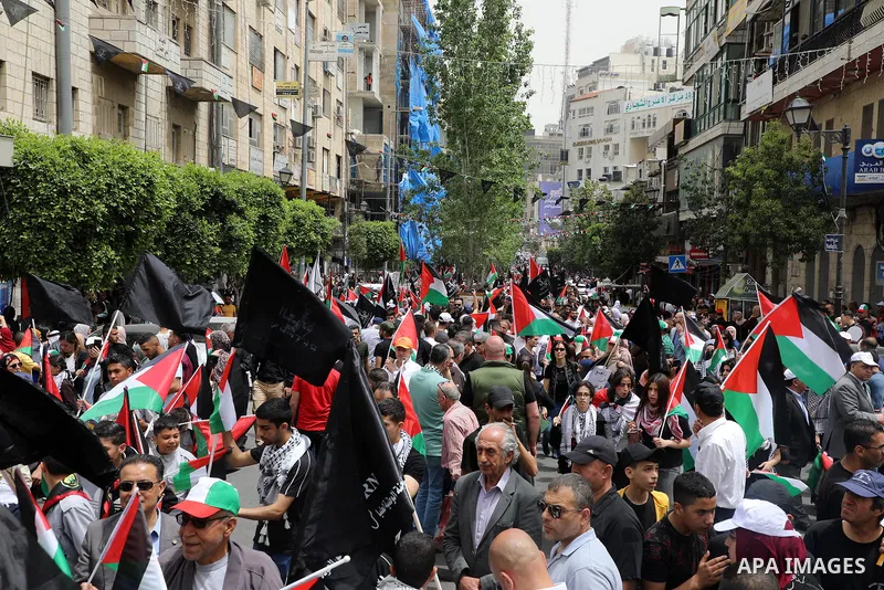Palestinians wave national flags as they march in a rally marking the 74th anniversary of the "Nakba" or "catastrophe", in the West Bank city of Ramallah, on May 15, 2022. Each year Palestinians commemorate the "Nakba" o...