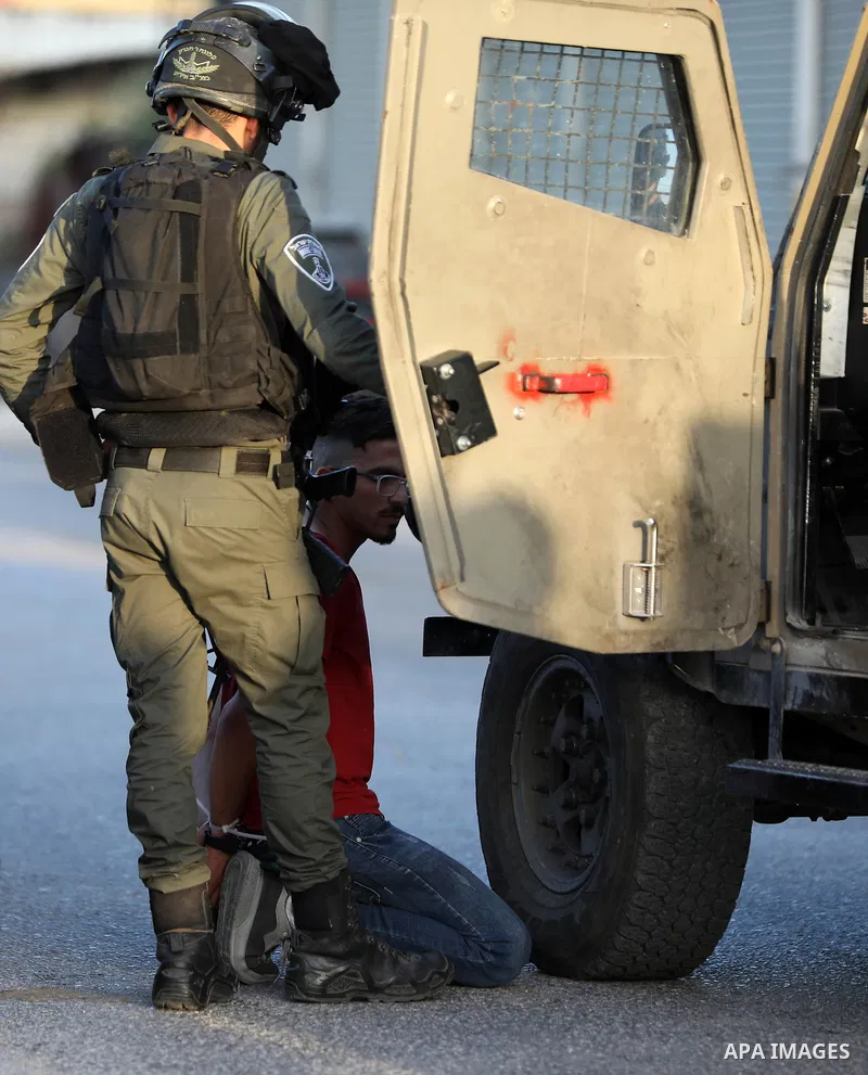 A member of Israel's security forces guards a prisoner during clashes with Palestinians after Israeli settlers attempted to remove Palestinian flags in Ezbet el-Tabib village east of the city of Qalqilya on May 31, 2022....