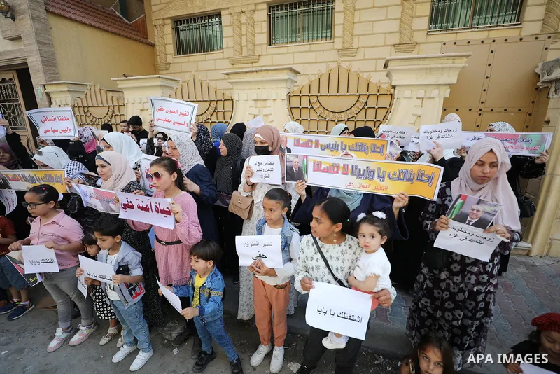 Palestinians hold banners to demand of the family reunification, in front of the civil affairs office, in Gaza city on June 6, 2022. Photo by Mahmoud Nasser