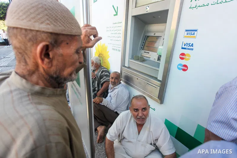 Palestinian of social affairs beneficiaries wait outside a bank to receive the payment of social affairs allowances for the first time in two years, in Gaza city, on July 6, 2022. Photo by Omar Ashtawy