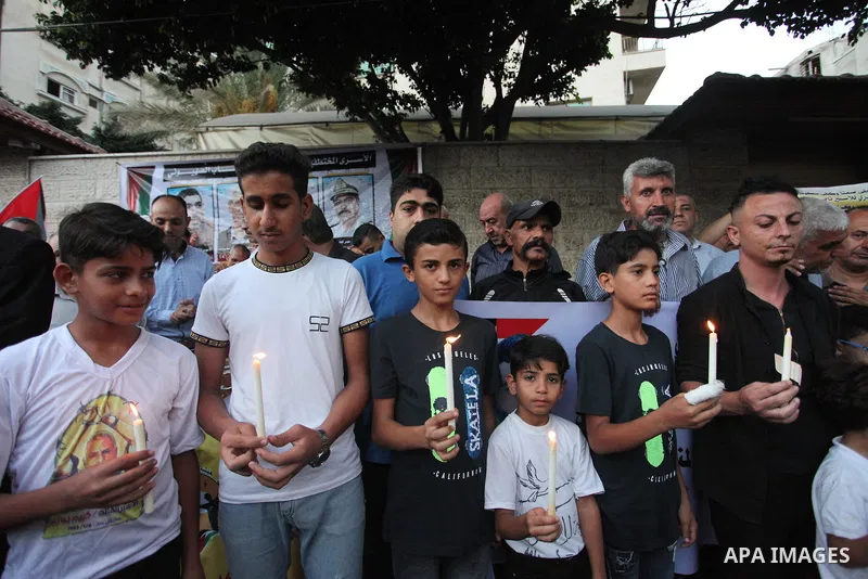 Palestinians hold banners and light candles during a protest in solidarity with Palestinian prisoner in Israeli jails suffering from cancer Nasser Abu Hamid, in front of Red cross office, in Gaza city on September 13, 20...