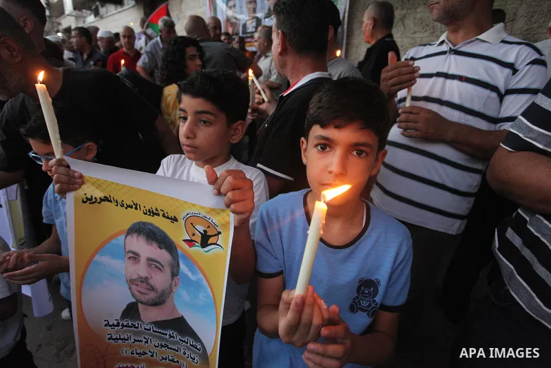 Palestinians hold banners and light candles during a protest in solidarity with Palestinian prisoner in Israeli jails suffering from cancer Nasser Abu Hamid, in front of Red cross office, in Gaza city on September 13, 20...